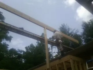 Carpenter setting a ridge beam over a new addition frame — Ice Dam Removal by Roofing Brothers in Ballston Lake