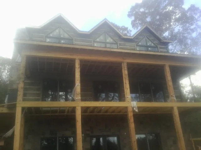 Dormers and porch framing on a large log home under construction — Roof Coating work by our crew in Ballston Lake