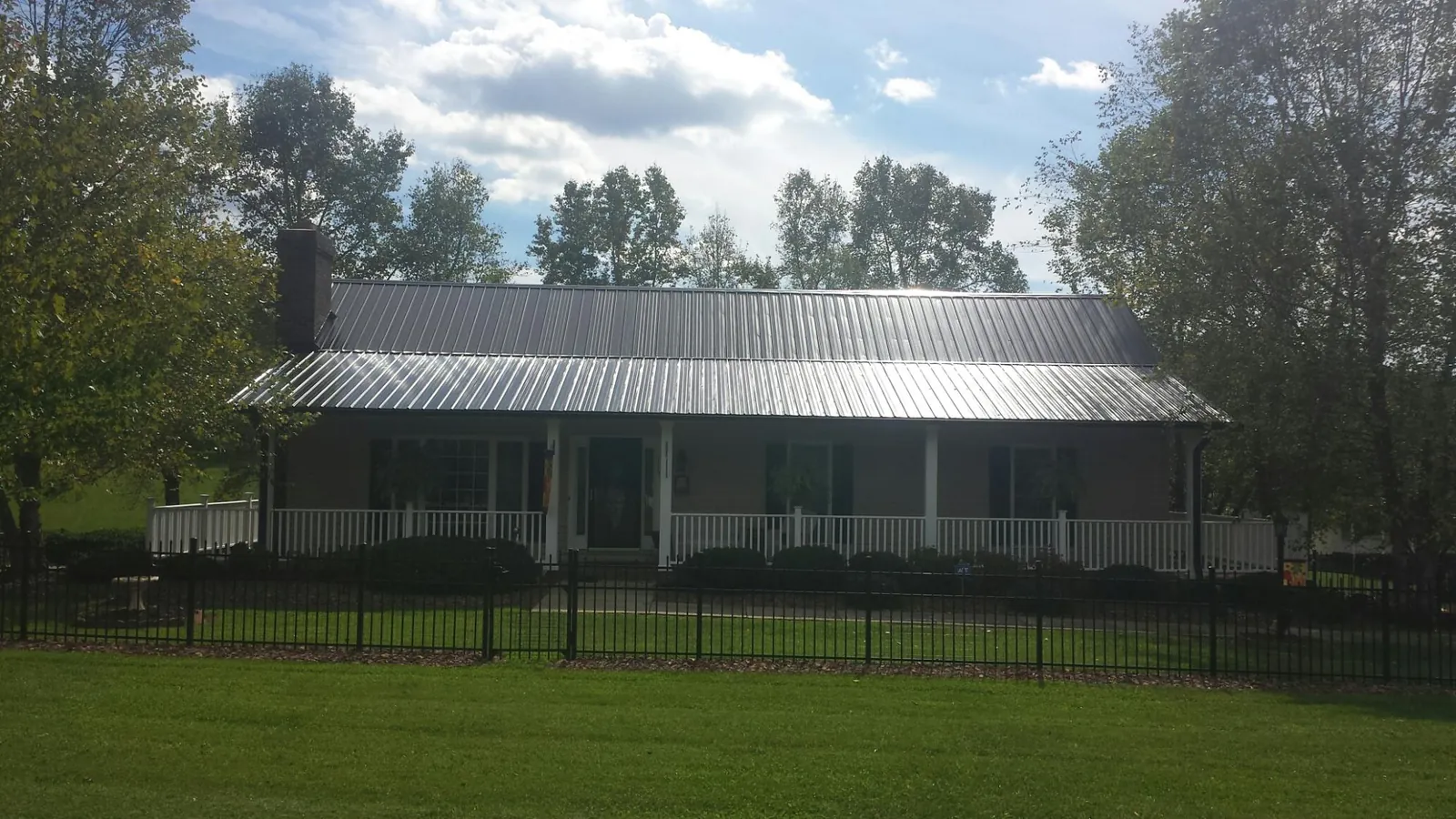 Gray metal roof on a brick ranch with a full width front porch — Gutter Guard Installation work by our crew in Ballston Lake