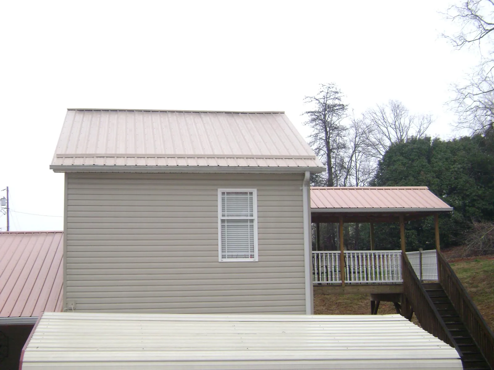 Tan metal roofs on a two story addition and attached porch, from a Roof Replacement job in Ballston Lake